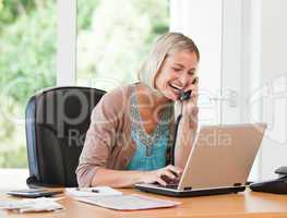 Woman working on her computer while she is phoning