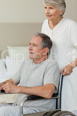 Retired man in his wheelchair with his wife