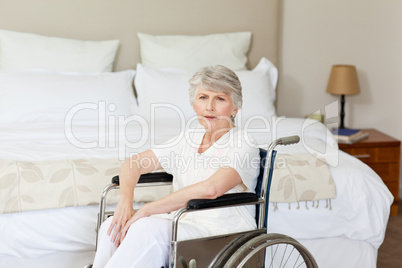 Concentrated senior woman in her wheelchair at home