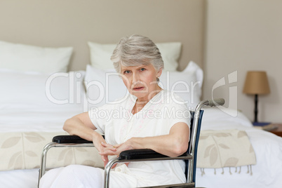 Concentrated senior woman in her wheelchair at home