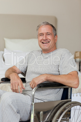 Smiling senior man in his wheelchair  at home