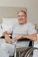 Smiling senior man in his wheelchair  at home