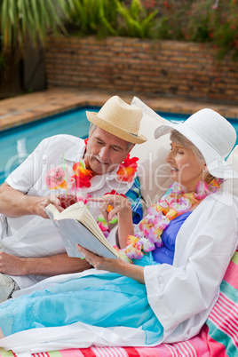 Mature woman reading a book while her husband is drinking a cock