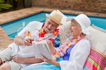 Mature woman reading a book while her husband is drinking a cock