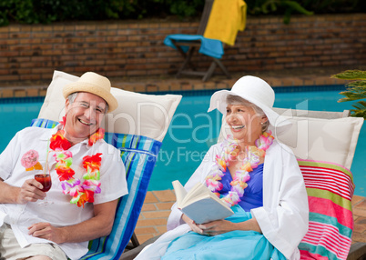 Mature woman reading a book while her husband is drinking a cock