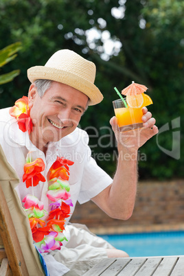 Mature man drinking a cocktail  beside the swimming pool