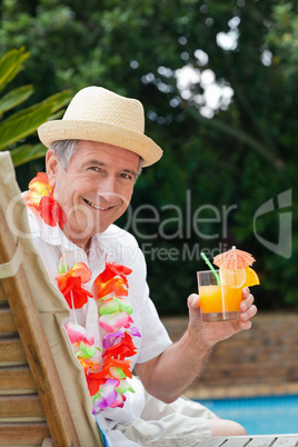 Mature man drinking a cocktail  beside the swimming pool