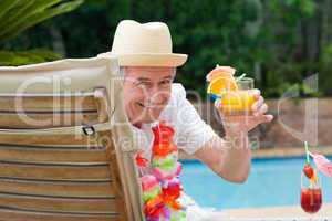 Mature man drinking a cocktail  beside the swimming pool