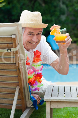 Mature man drinking a cocktail  beside the swimming pool