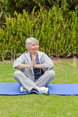 Retired woman practicing yoga in the garden