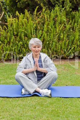 Retired woman practicing yoga in the garden