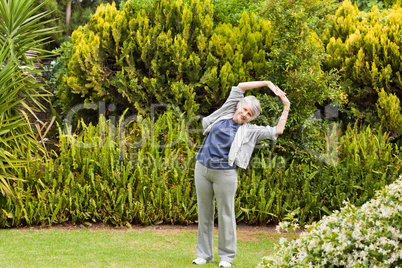 Retired woman doing her streches in the garden Retired woman doing her streches in the garden