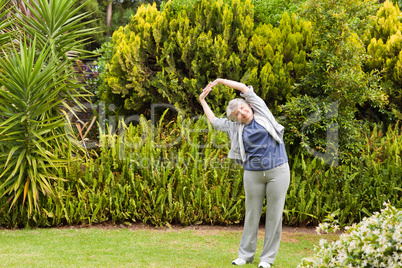 Retired  woman doing her streches in the garden