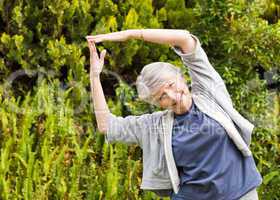 Mature woman doing her streches in the garden