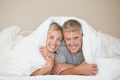 Couple lying down in their bed at home