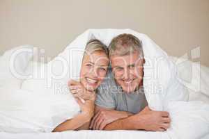 Couple lying down in their bed at home