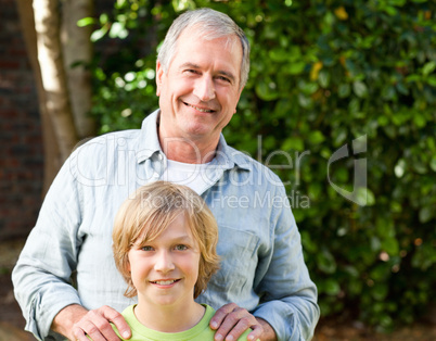 Grandfather with his grandson looking at the camera in the garde