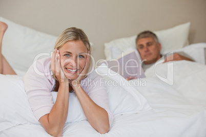 Pretty woman looking at the camera while her husband is sleeping