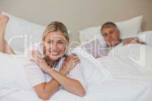 Pretty woman looking at the camera while her husband is sleeping