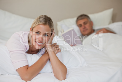 Pretty woman looking at the camera while her husband is sleeping