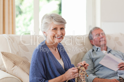 Woman knitting while her husband is sleeping