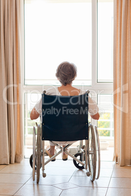 Mature woman in her wheelchair with her back to the camera