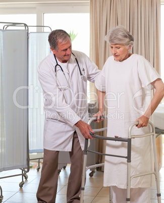 Senior doctor helping his patient to walk