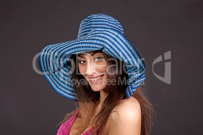 Pretty young smiling girl in hat on dark