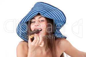Pretty girl in hat eating chocolate cake isolated on white