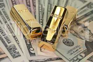 drei Goldbarren auf Dollarscheinen