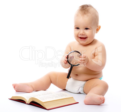 Little child play with book and magnifier