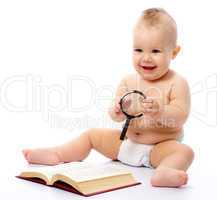 Little child play with book and magnifier