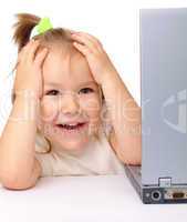 Cute little girl is looking out from her laptop