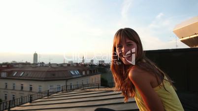 Eine lachende, junge Frau auf dem Hausdach