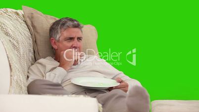 Mann isst auf dem Sofa