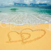 two hearts drawn in a sandy tropical beach