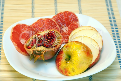 Sliced grapefruit, pomgranate and apple on white dish