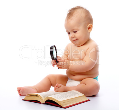 Little child play with book and magnifier