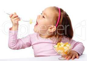 Little girl eats fruit salad