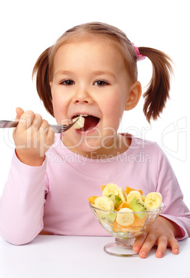 Little girl eats fruit salad