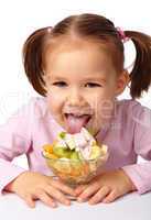 Little girl licks fruit salad