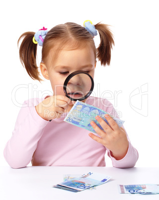 Girl is looking at euro banknote using magnifier