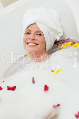 Pretty woman taking a relaxing bath with a towel on her head