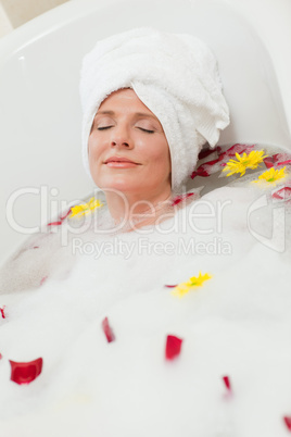 Pretty woman taking a relaxing bath with a towel on her head