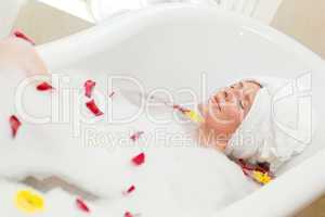 Pretty woman taking a relaxing bath with a towel on her head