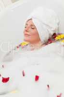 Pretty woman taking a relaxing bath with a towel on her head