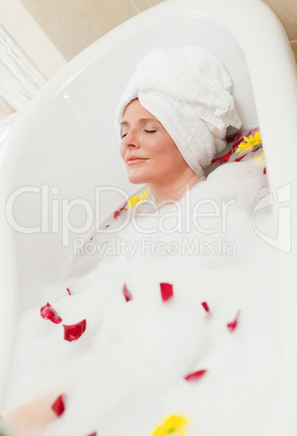 Pretty woman taking a relaxing bath with a towel on her head