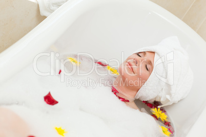 Pretty woman taking a relaxing bath with a towel on her head