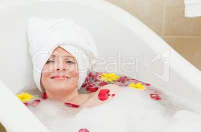 Relaxed woman taking a relaxing bath with a towel on her head