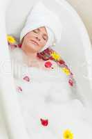 Relaxed woman taking a relaxing bath with a towel on her head